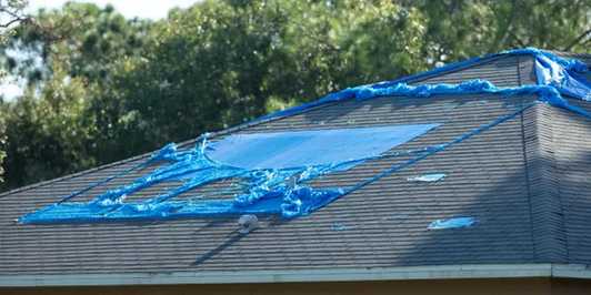 Photo of a tarp meticulously placed on a roof to protect a damaged area until a roofer can repair